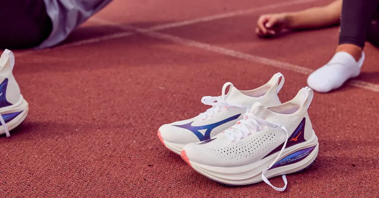 Białe buty do biegania Mizuno Neo Vista 2 z niebieskimi akcentami na bieżni.