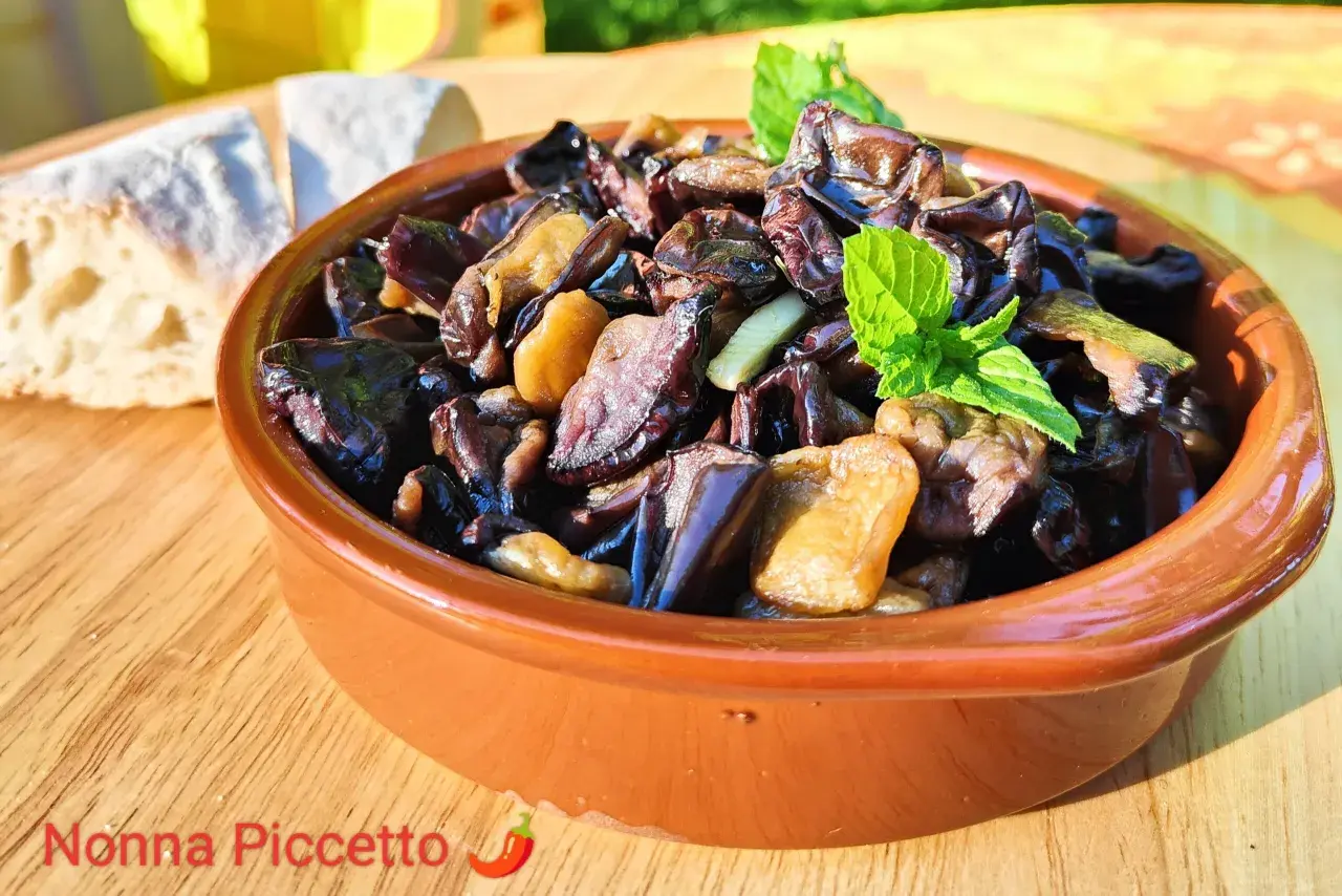 Melanzane alla scapece in terracotta, guarnite con menta fresca, accanto a pane casereccio. Un piatto estivo che profuma di tradizione.