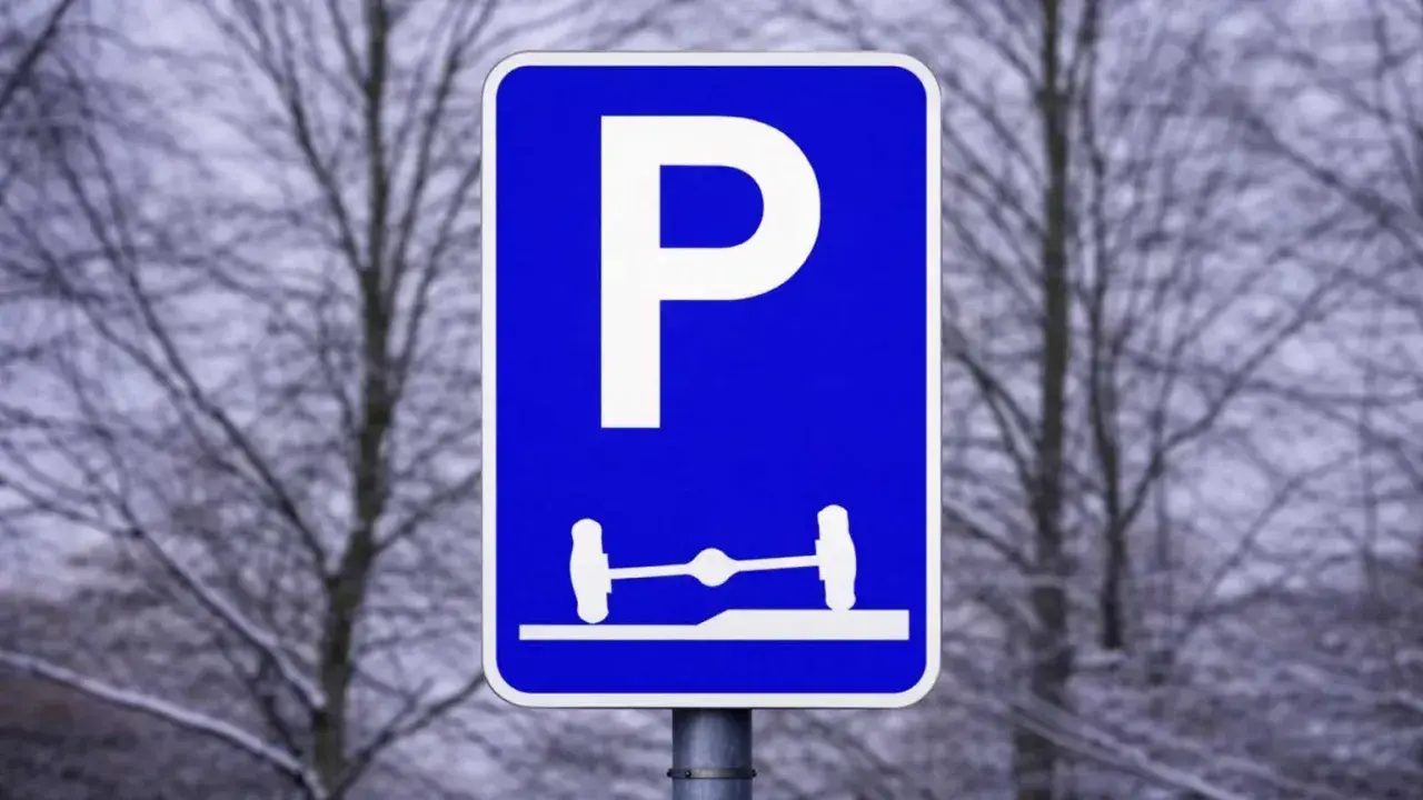 Blå parkeringsskylt med vitt P och en bild av en axel med hjul på en ramp. Förståelse av parkeringsskyltar är viktigt för att veta var man får parkera.