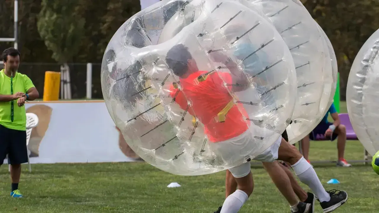 Gracze w wielkich, przezroczystych kulach zderzają się podczas gry w bubble football.