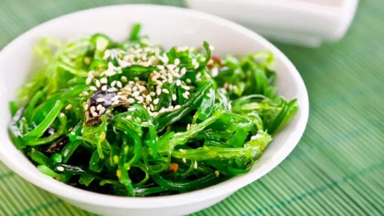 A vibrant green seaweed salad, sprinkled with sesame seeds, perfect for healthy kelp recipes.