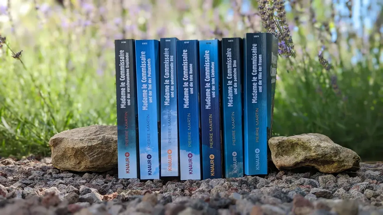 Reihenfolge der "Madame le Commissaire"-Bücher von Pierre Martin, aufgestellt zwischen Steinen und Lavendel.
