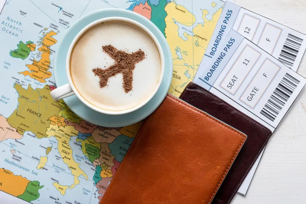 Une tasse de café avec un avion en cacao sur une carte du monde, à côté de billets d'avion. L'idée d'un voyage, d'une carte pass et étape.
