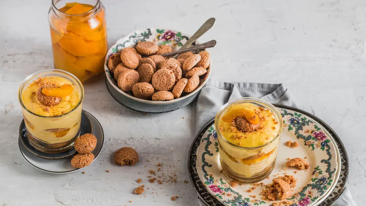 Delizioso tiramisù alle pesche in bicchiere, con amaretti e pesche sciroppate.