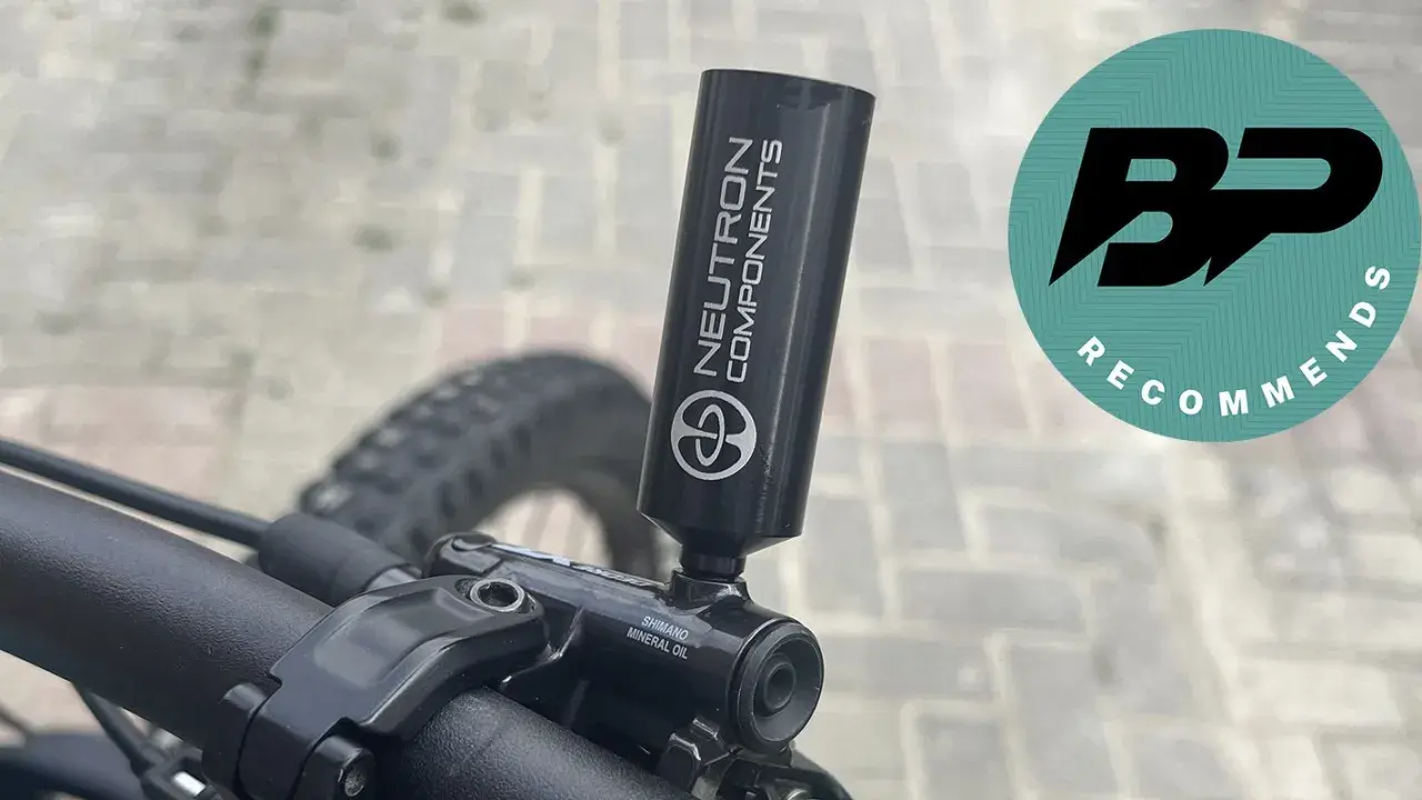 Close-up of a bicycle's mineral oil brake system with a "Neutron Components" tool attached.