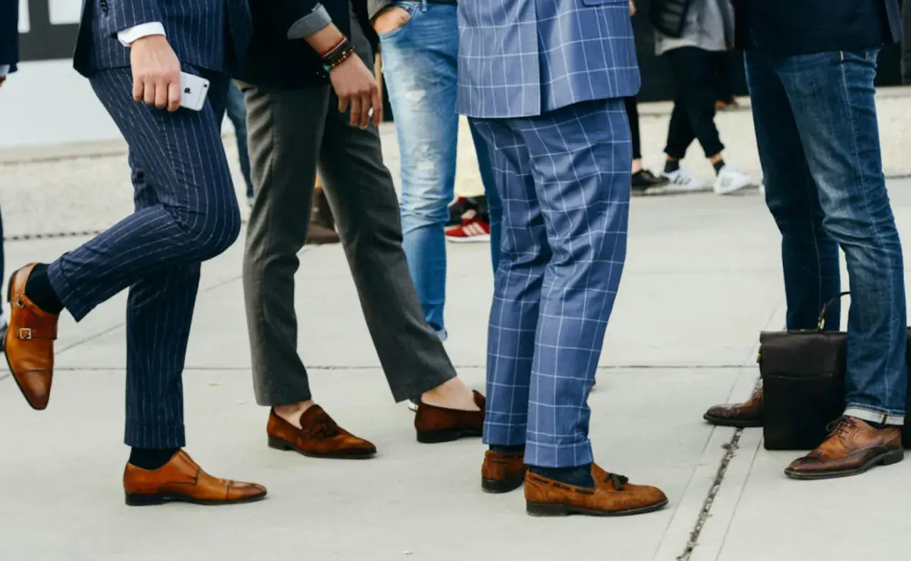 Un groupe d'hommes élégants, leurs pantalons tombant sur leurs chaussures, arborent des styles variés, du costume à rayures aux jeans.