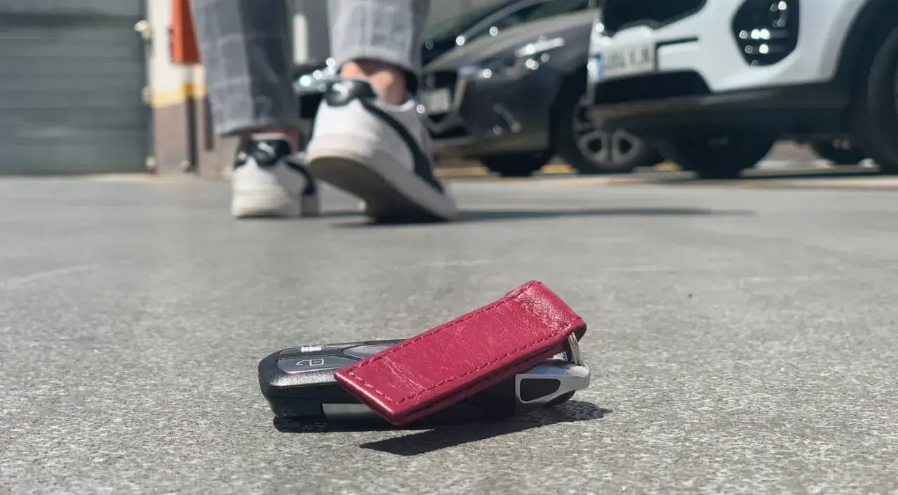 ¡Ay no! He perdido las llaves del coche. Están tiradas en el suelo, cerca de unos zapatos y coches aparcados.