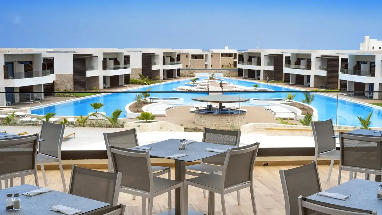 Luksusowy resort Royal Horizon Ponta Sino z basenem i barem. Stoły na tarasie czekają na gości.