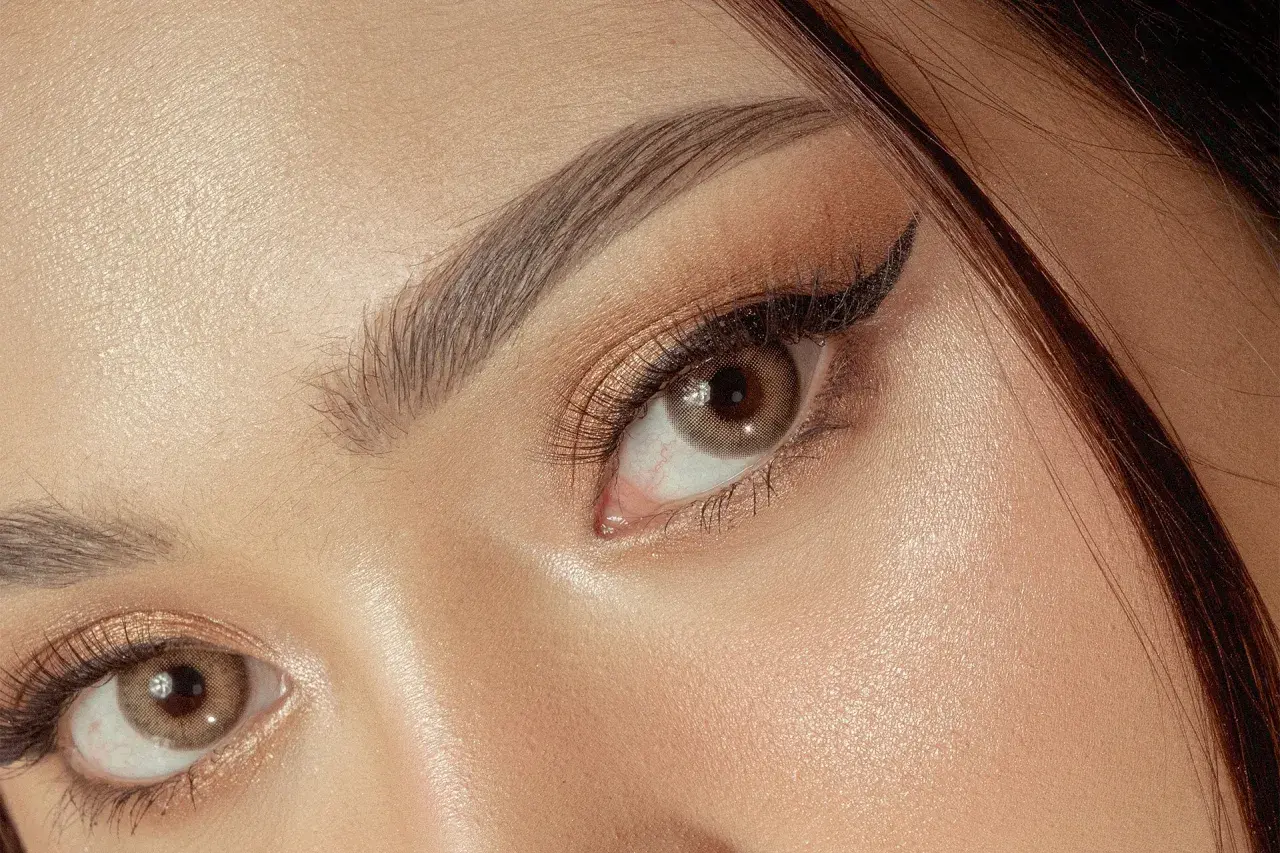 Un maquillage yeux sophistiqué avec un trait d'eye-liner fin et des fards dorés scintillants.