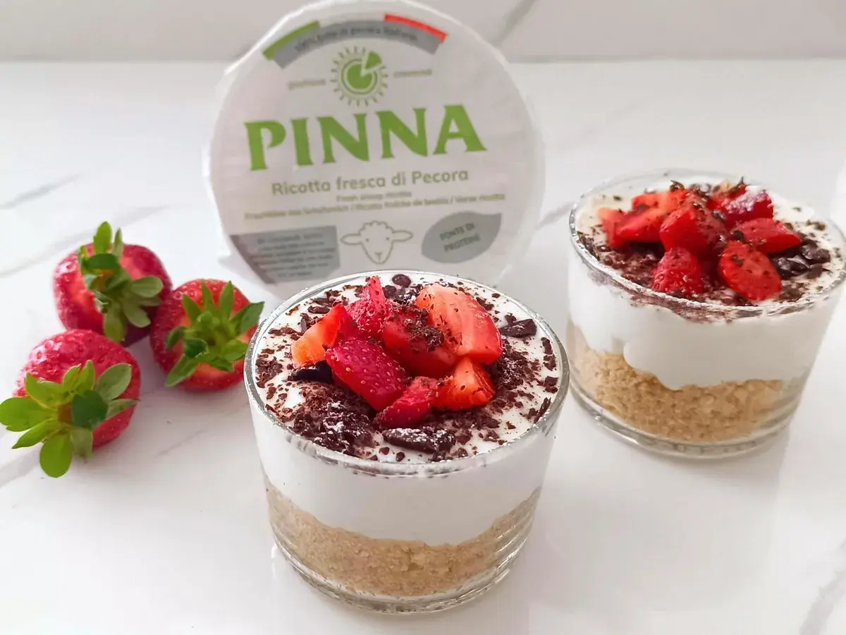 Delizioso dolce al bicchiere con ricotta fresca, fragole e scaglie di cioccolato. Perfetto per un dessert leggero e gustoso.