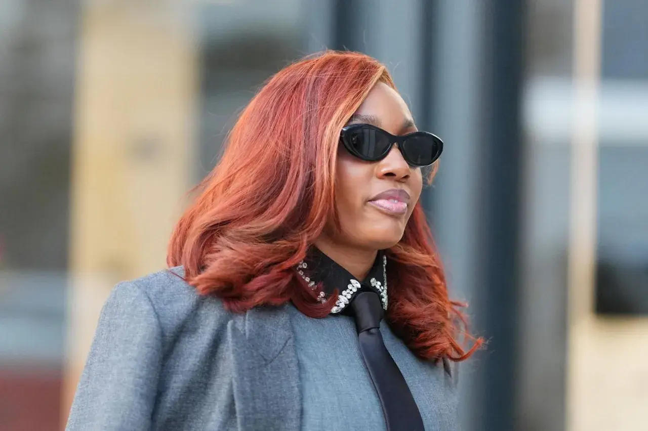 Feuerrote Haare, auffällige Sonnenbrille und ein Blazer – diese Frau verkörpert den Trend für Frisuren 2026.