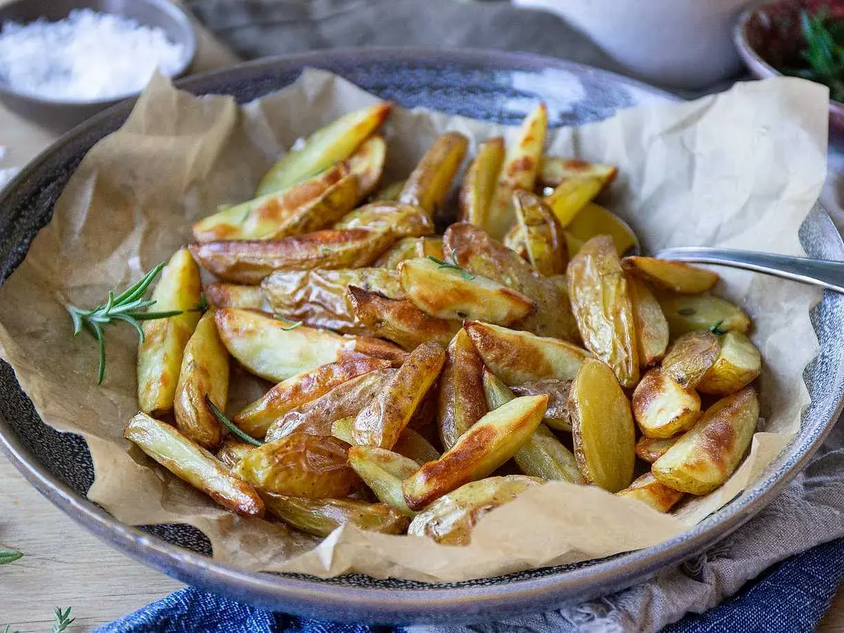 Klyftpotatis i airfryer, gyllene och krispiga, serverade med färsk rosmarin. Perfekt tillbehör!