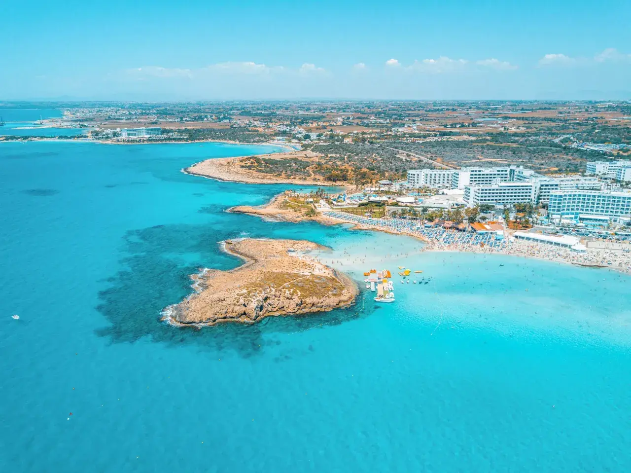 En livlig strand med turkost vatten, solbadande och vattensporter. Perfekt för Ayia Napa aktiviteter.
