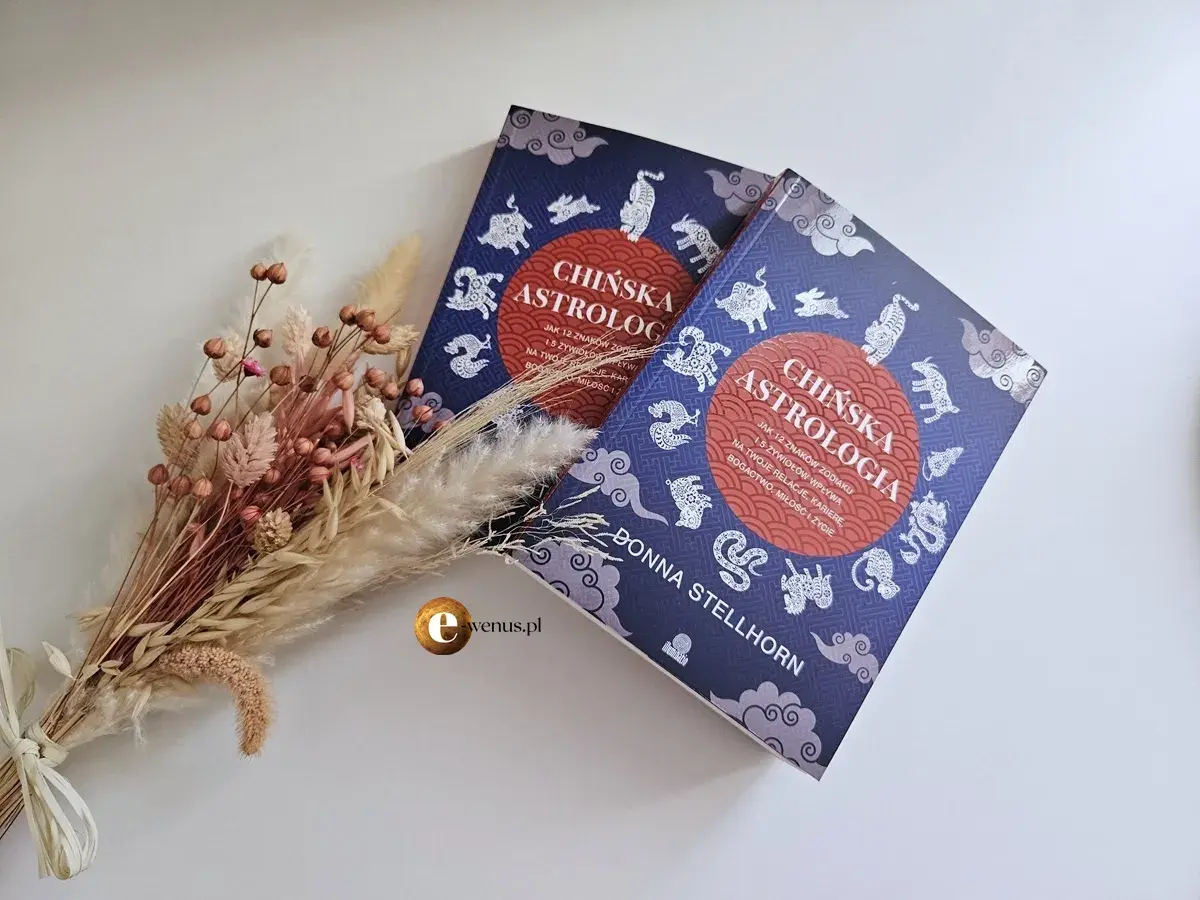 Dwie książki o chińskiej astrologii, odkrywające wpływ 12 znaków i wszystkich żywiołów na życie, obok bukietu suszonych kwiatów.