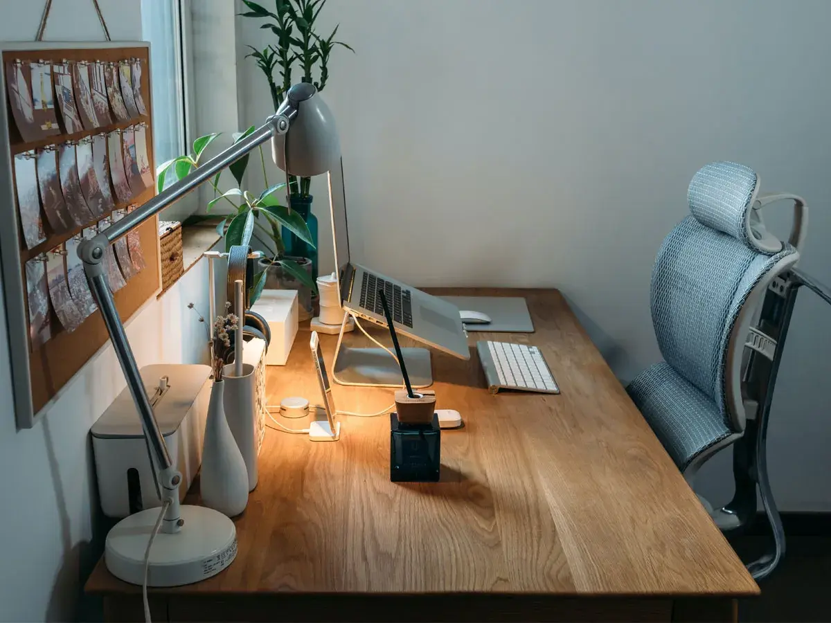 Bureau en bois avec plan de travail, ordinateur portable, lampe, clavier et chaise ergonomique. Une idée d'espace de travail fonctionnel et esthétique.