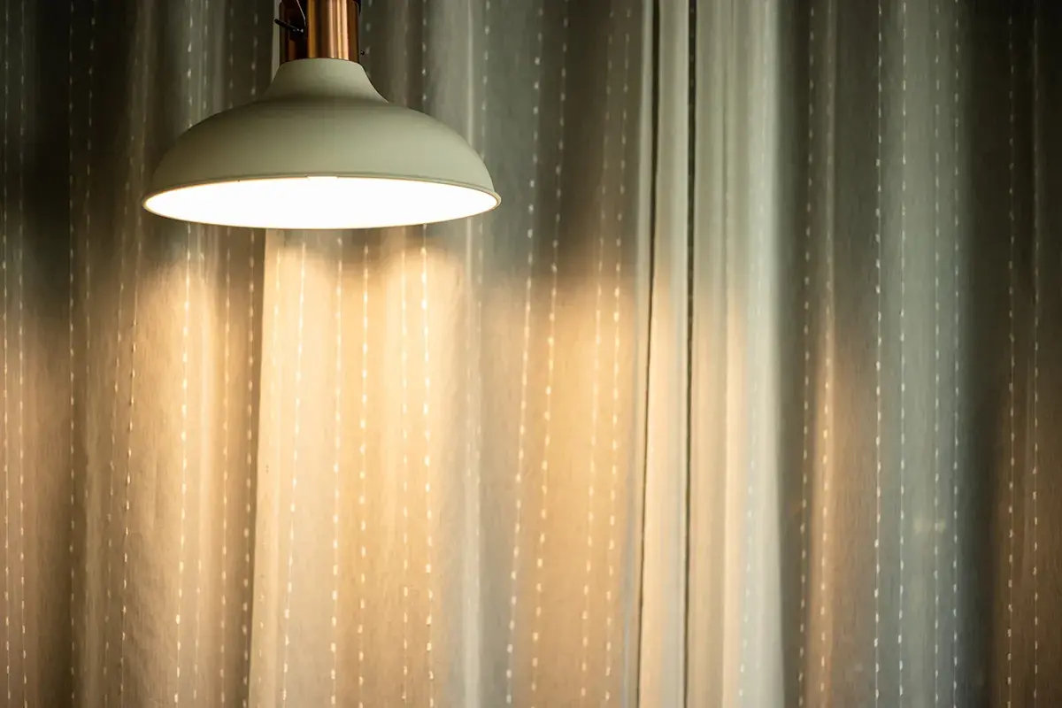 Jasna lampa wisząca rzuca ciepłe światło na zasłony. Czy 3000 lumenów to dużo? To dużo światła do stworzenia przytulnej atmosfery.