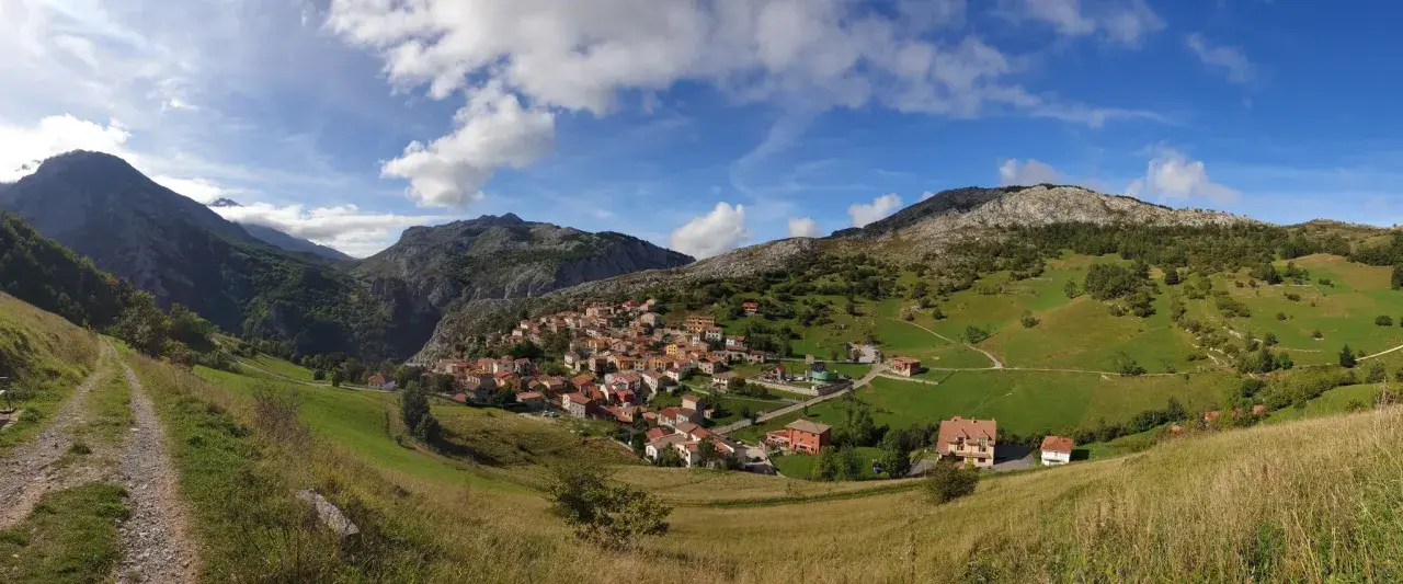 Pueblo de Sotres en los Picos de Europa, ideal para explorar sus rutas. Casas de piedra y tejados rojos entre verdes prados y montañas.