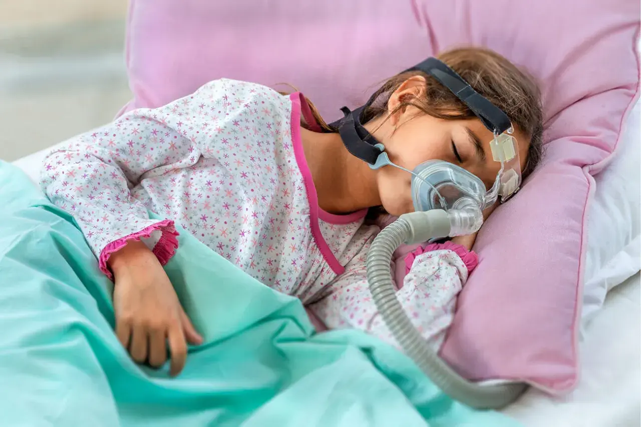 Dziecko śpi z maską CPAP, która pomaga mu oddychać podczas snu, łagodząc bezdech u dziecka.
