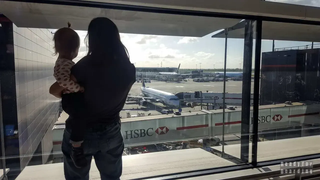 Mama z dzieckiem na rękach patrzy na samoloty. Czas na boarding, przygoda czeka!