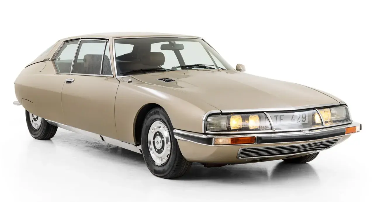 En beige Citroën SM, en av många ikoniska Citroën modeller, med sina distinkta linjer och strålkastare.