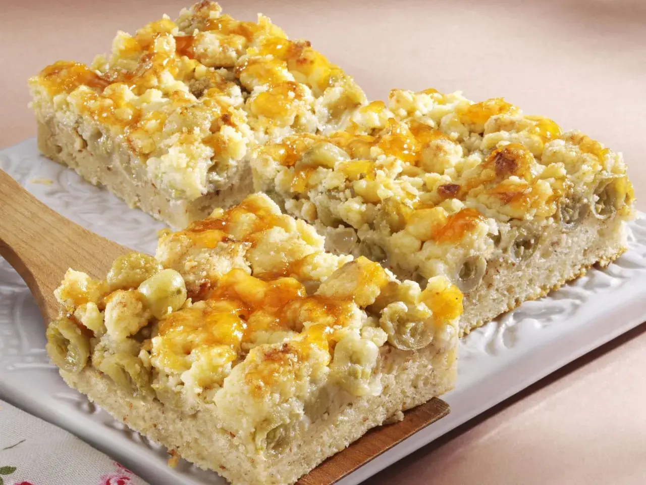 Saftiger Stachelbeerkuchen mit Streuseln, goldbraun gebacken und mit einem Hauch von Honigglanz überzogen.