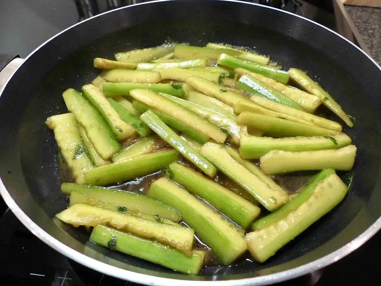 Tranches de concombre cuit dans une poêle, prêtes pour une recette savoureuse.