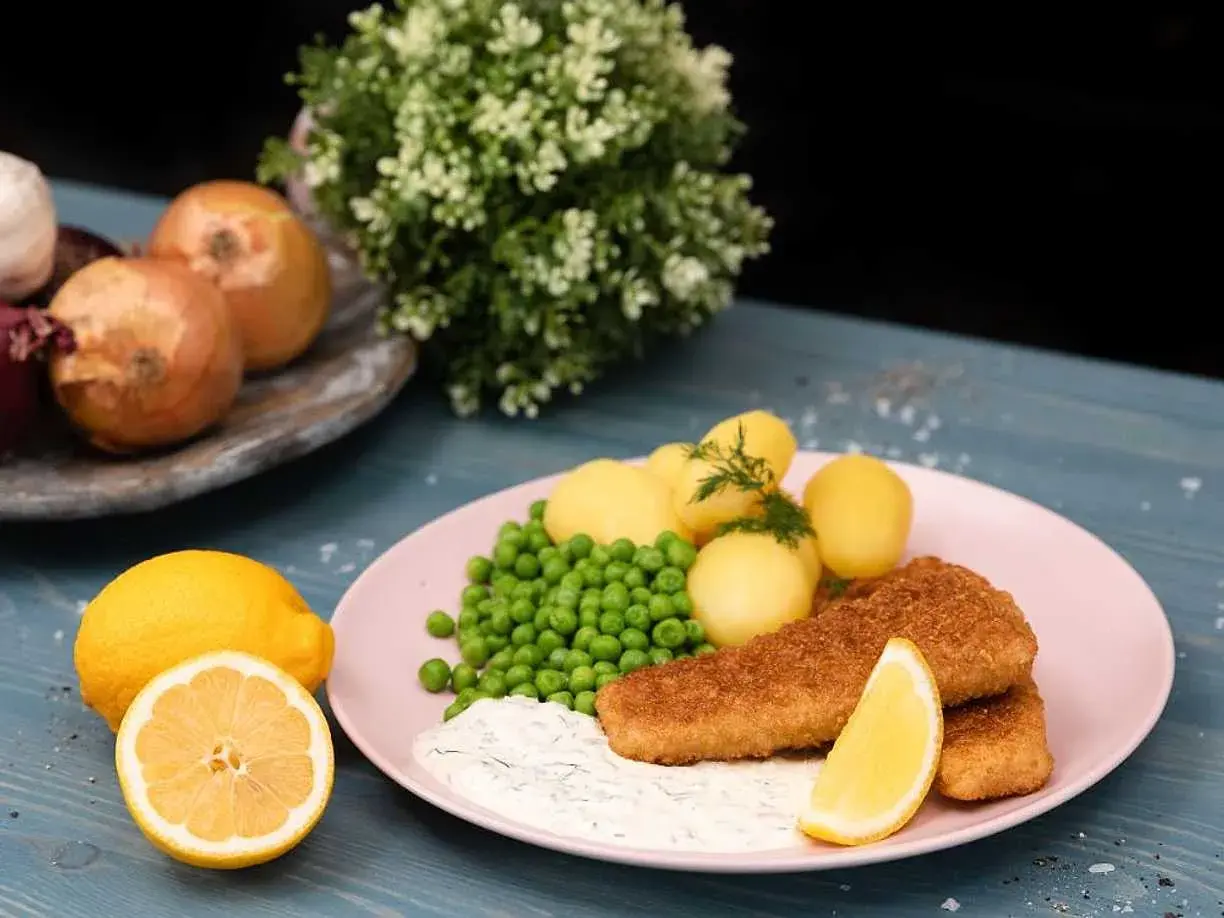 Panerad fisk med kokt potatis, gröna ärtor och en krämig sås som påminner om skolans kalla fisksås. Serveras med citron.