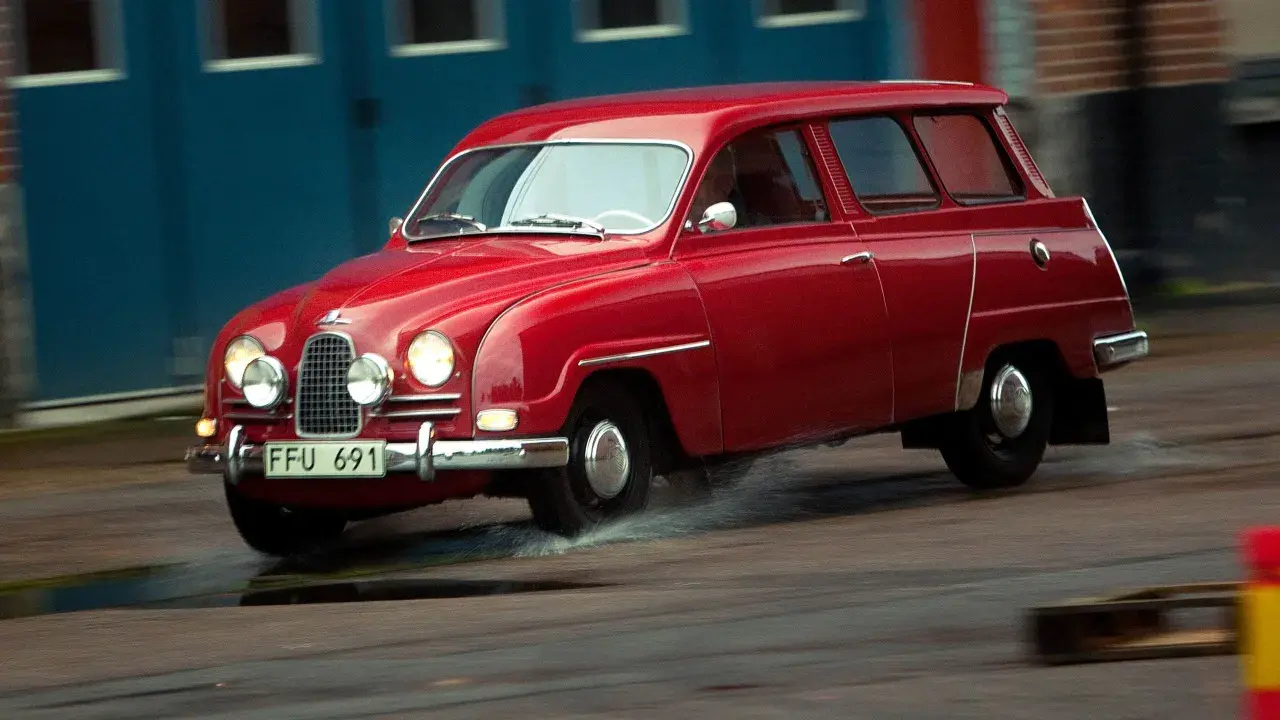 Röd Saab 2-takt kombi kör genom vattenpölar.