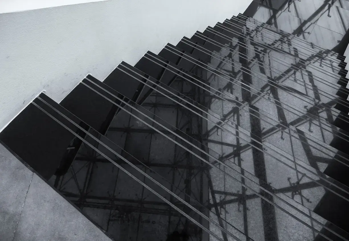 Ciemne schody z polerowanego konglomeratu odbijają architektoniczne detale, tworząc geometryczne wzory.