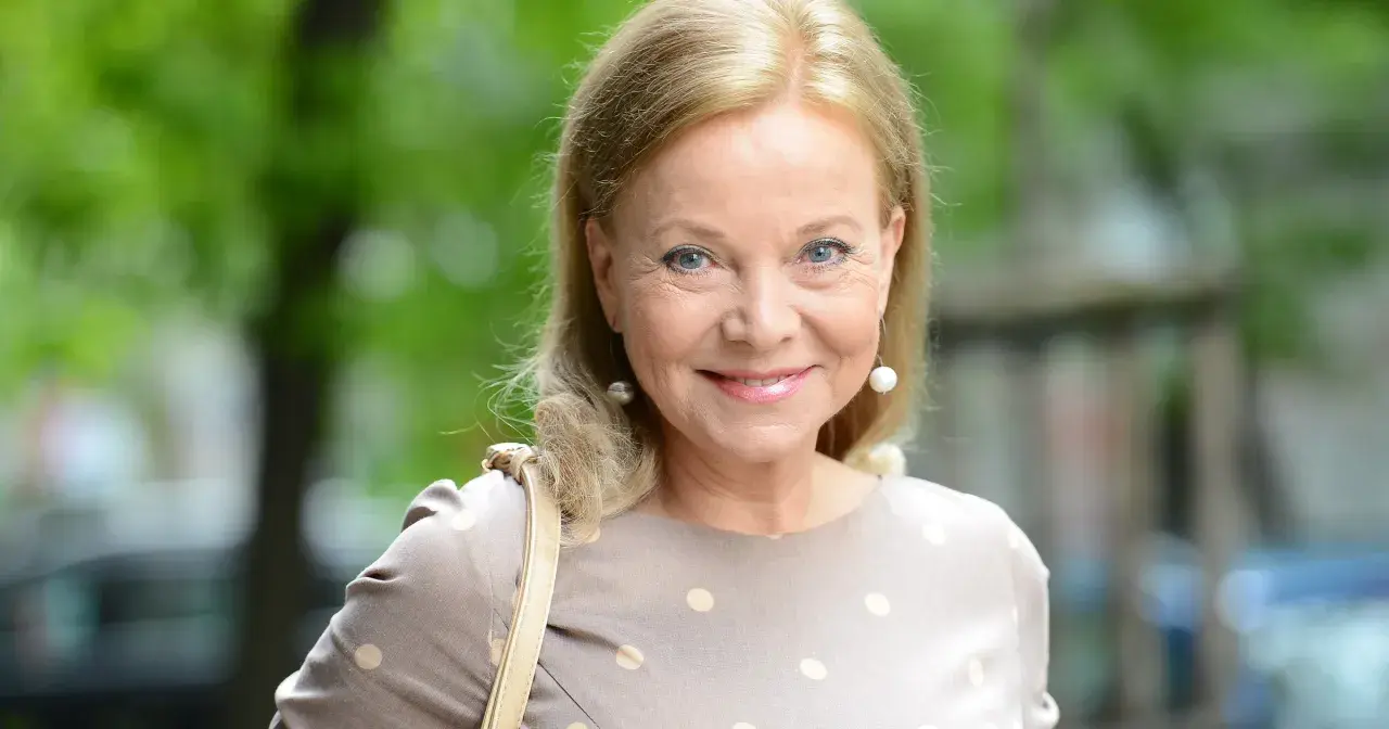 Portret Laury Łącz w beżowej sukience w groszki, z perłowymi kolczykami.