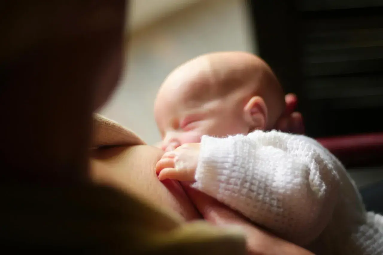 Un neonato dorme serenamente mentre viene allattato. Un momento intimo che fa riflettere su cosa mangiare in allattamento per il benessere di entrambi.