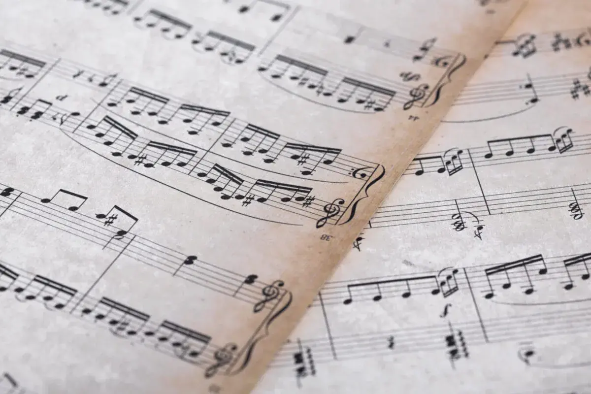 Feuilles de musique anciennes avec des portées et des notes. On y distingue un dessin de clef d'ut.