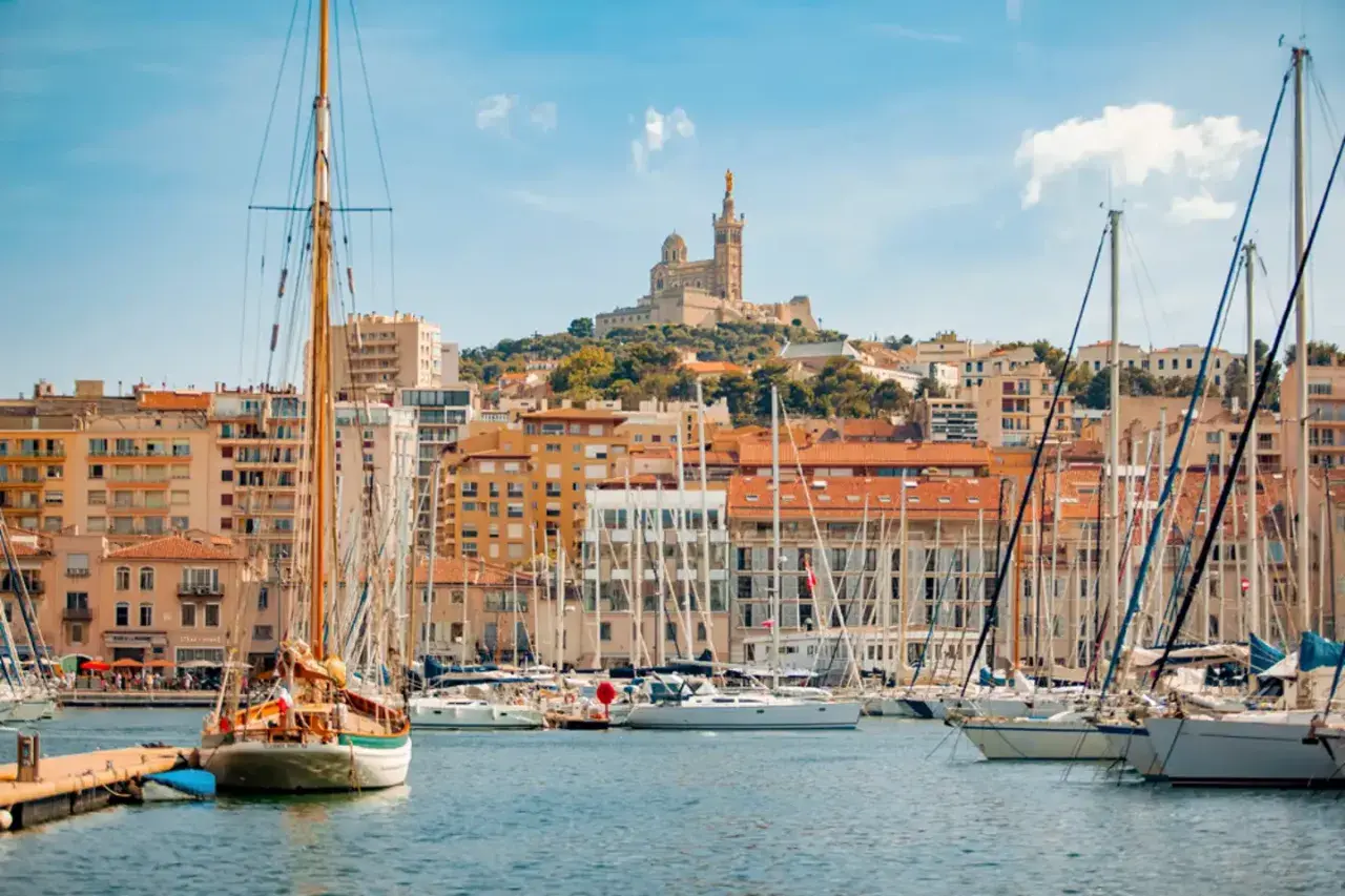 Segelboote im Hafen von Marseille, mit der Basilika Notre-Dame de la Garde im Hintergrund. Hier kann man viel unternehmen!