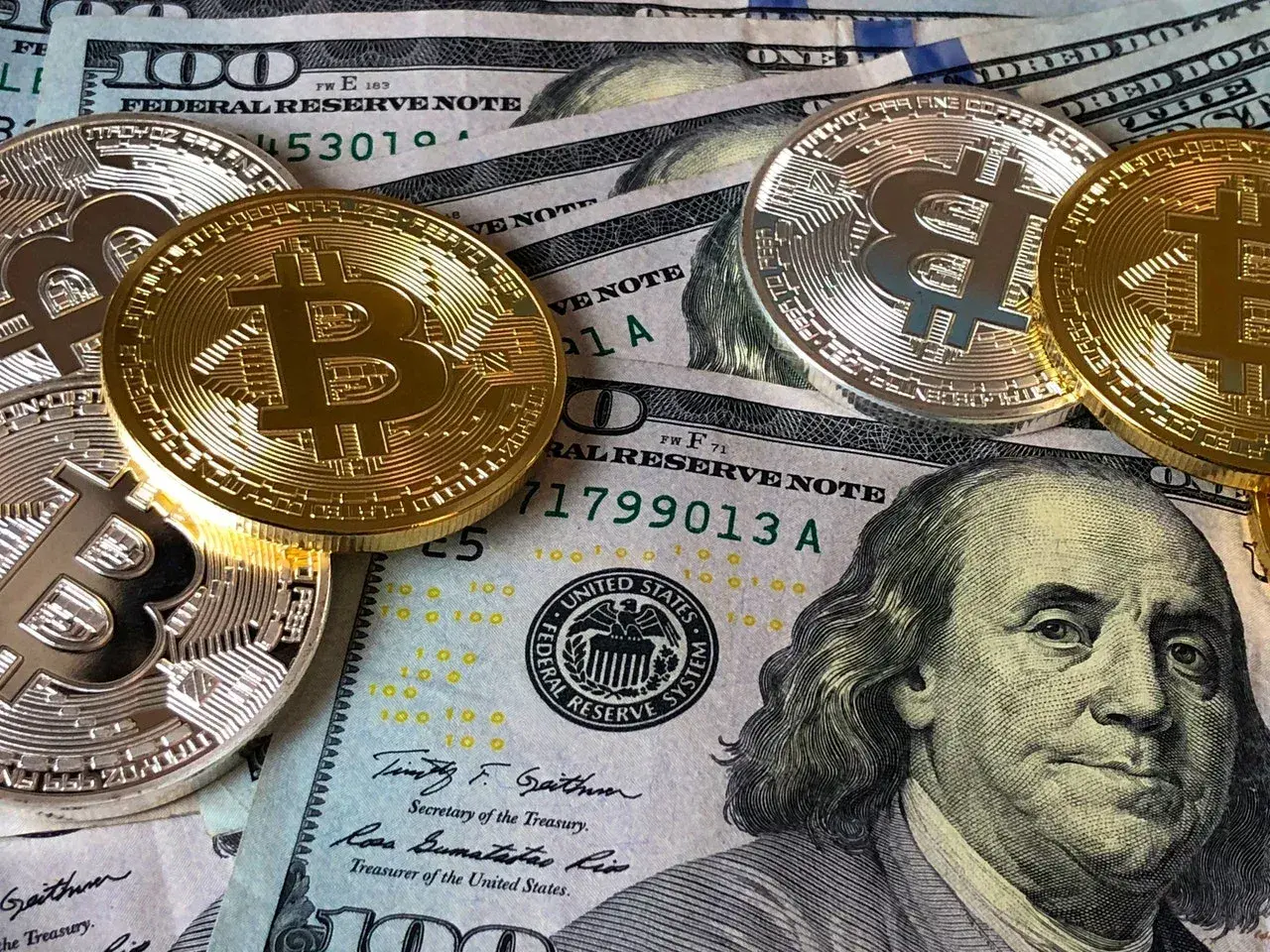Złote i srebrne monety z symbolem Bitcoina leżą na banknotach dolarowych. Czy to przyszłość płatności w kantorze Santander Bank?