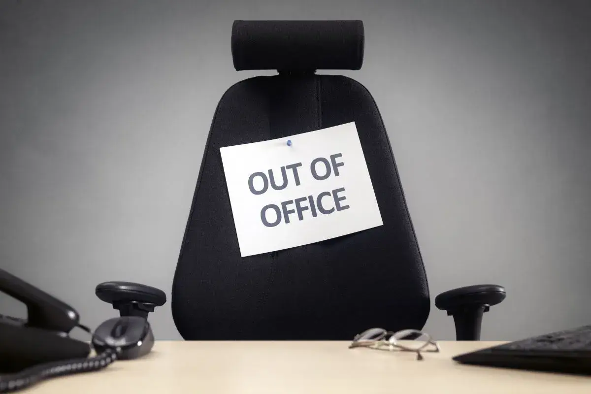 Puste biurowe krzesło z kartką "OUT OF OFFICE". Czas na zasłużone święta w sierpniu!