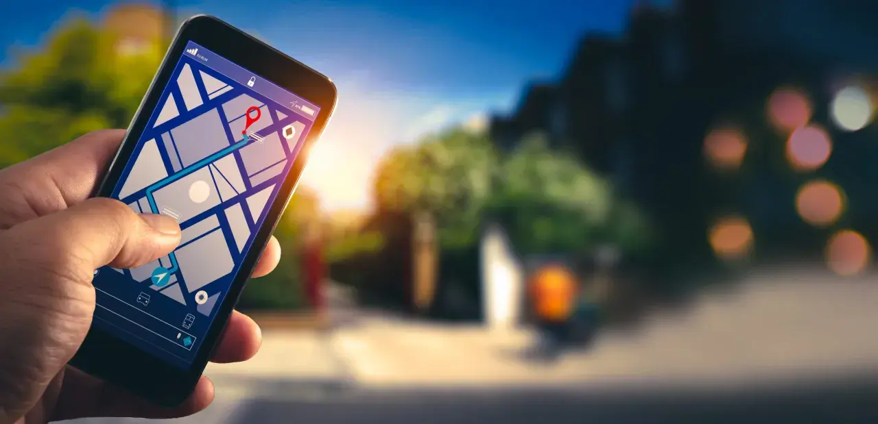 Dłoń trzyma smartfon z mapą i trasą. Dowiedz się, jak włączyć nawigację w telefonie, by łatwo dotrzeć do celu.