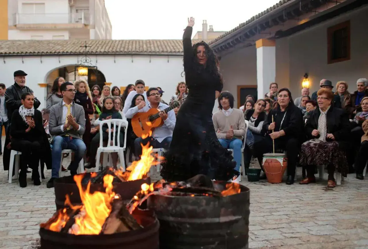 Bailarina flamenca actuando junto a hogueras, con guitarrista y público. Ambiente de villancicos flamencos jerezanos.