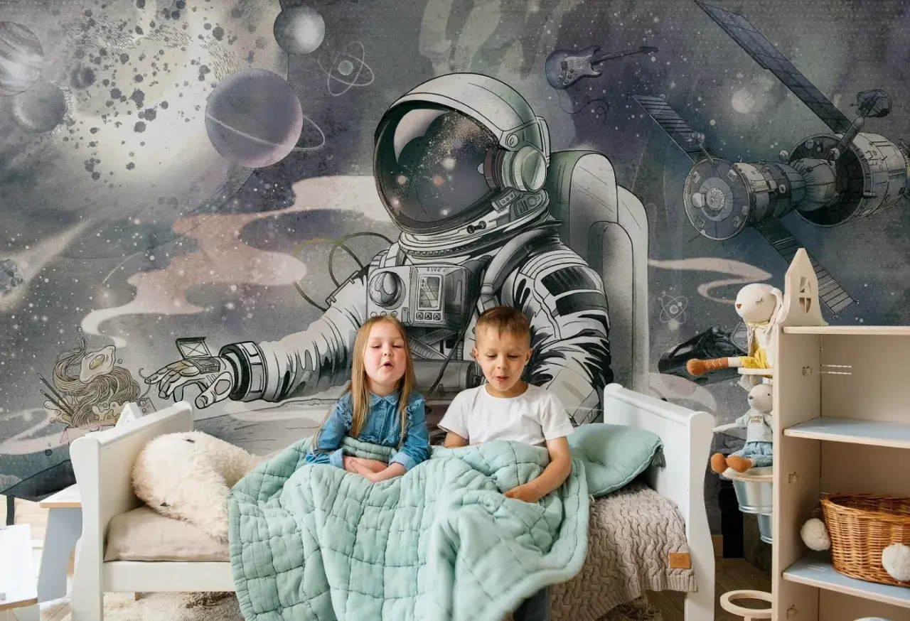 Dzieci siedzą pod kołdrą na łóżku, a za nimi wspaniała tapeta kosmos dla dzieci z astronautą i planetami.