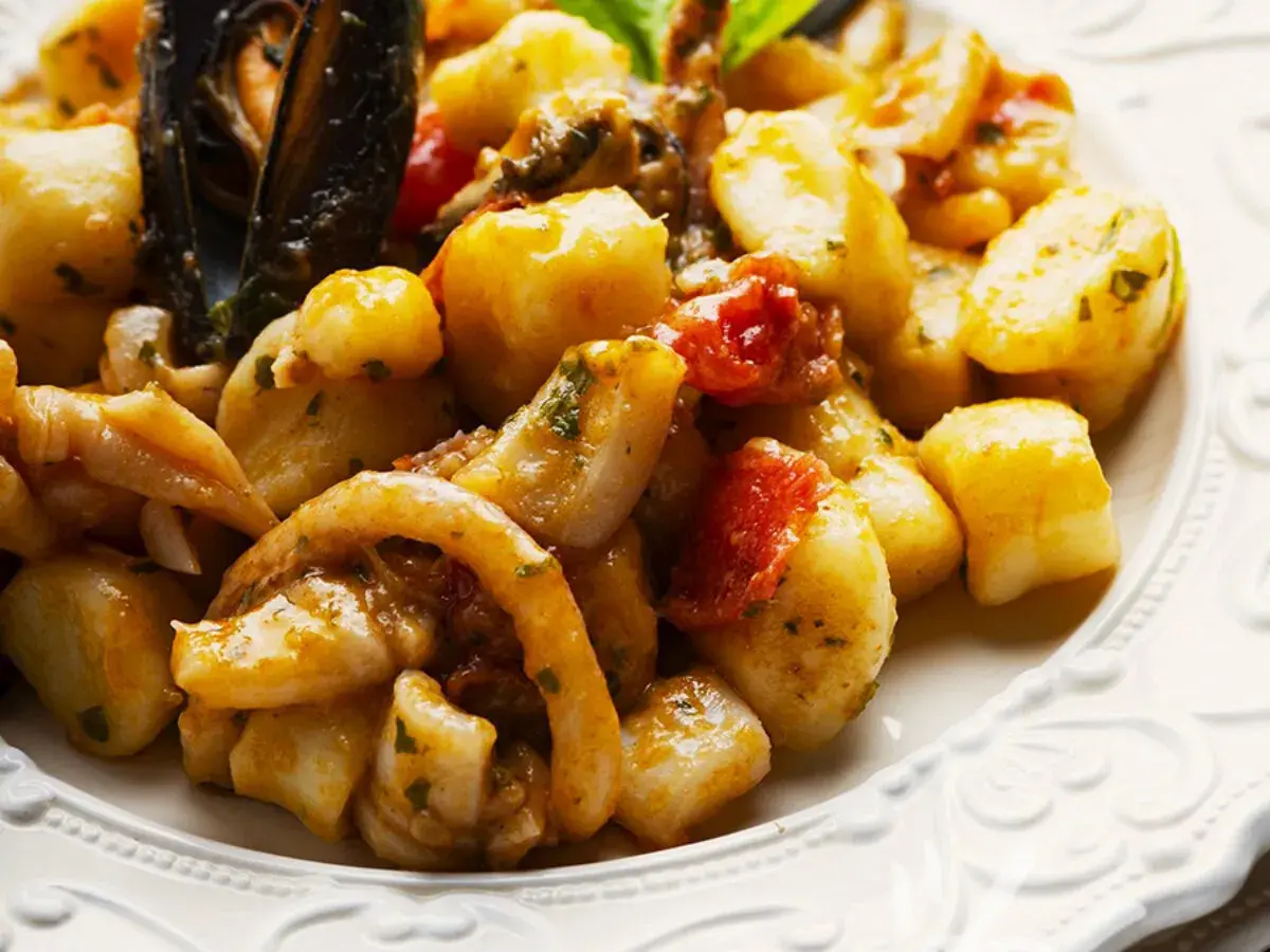 Gnocchi allo scoglio con cozze, calamari e pomodorini, un piatto ricco di sapori marini.