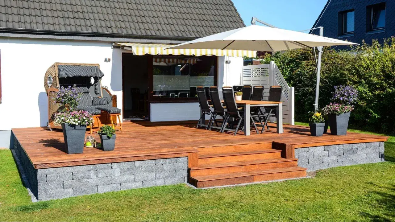 Eine schöne Holzterrasse mit Sitzmöbeln und Pflanzen, die zeigt, wie man eine Terrasse gestalten mit wenig Geld kann.