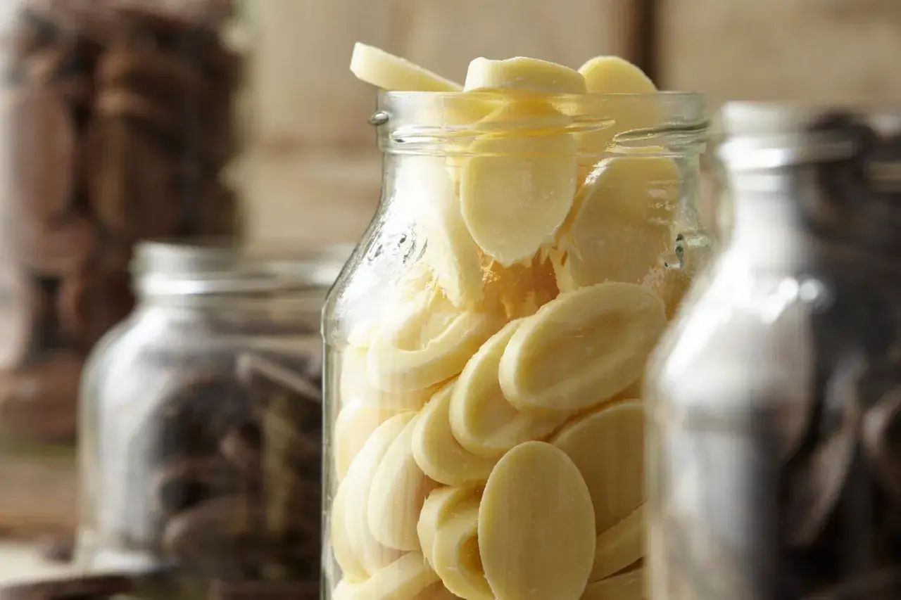Des éclats de chocolat blanc dans un bocal, prêts pour la conservation. Le chocolat maison est un délice.