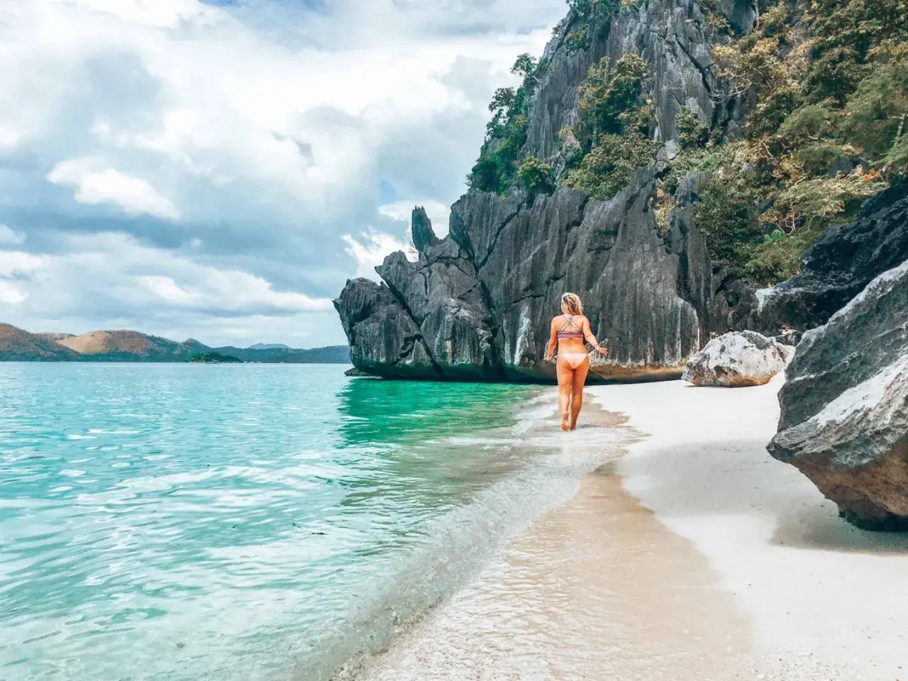 Frau genießt das türkisfarbene Wasser und den weißen Sandstrand auf den Philippinen. Ein perfekter Ort für Backpacking-Abenteuer.