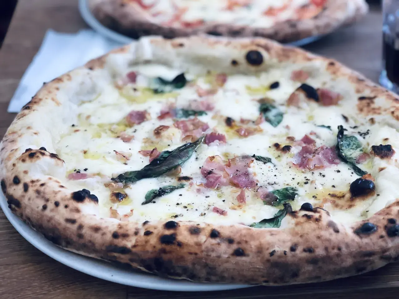 En ljuvlig pizza med bubblig lilla napoli deg, toppad med ost, bacon och basilika. Perfekt för en mysig kväll.