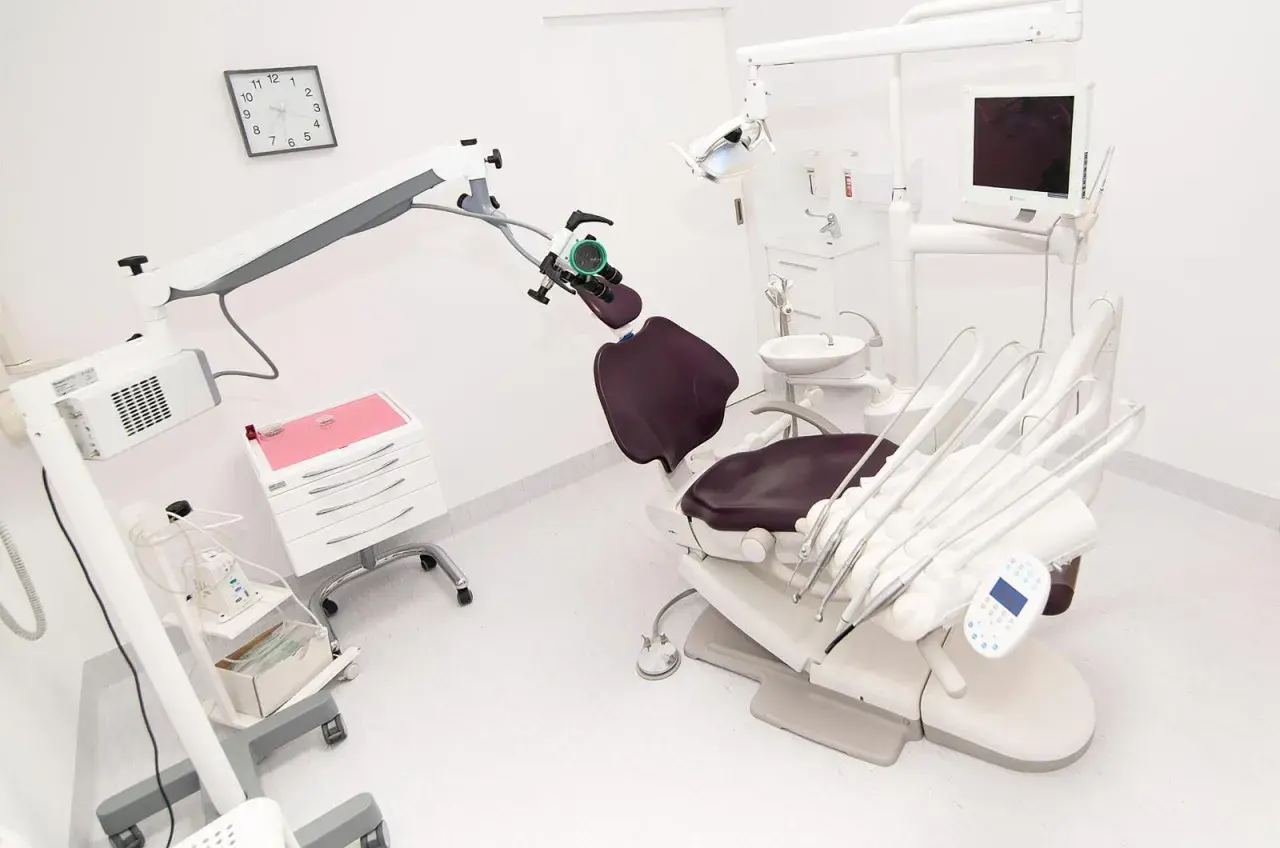 Nowoczesny gabinet stomatologiczny z fotelem, mikroskopem i sprzętem.