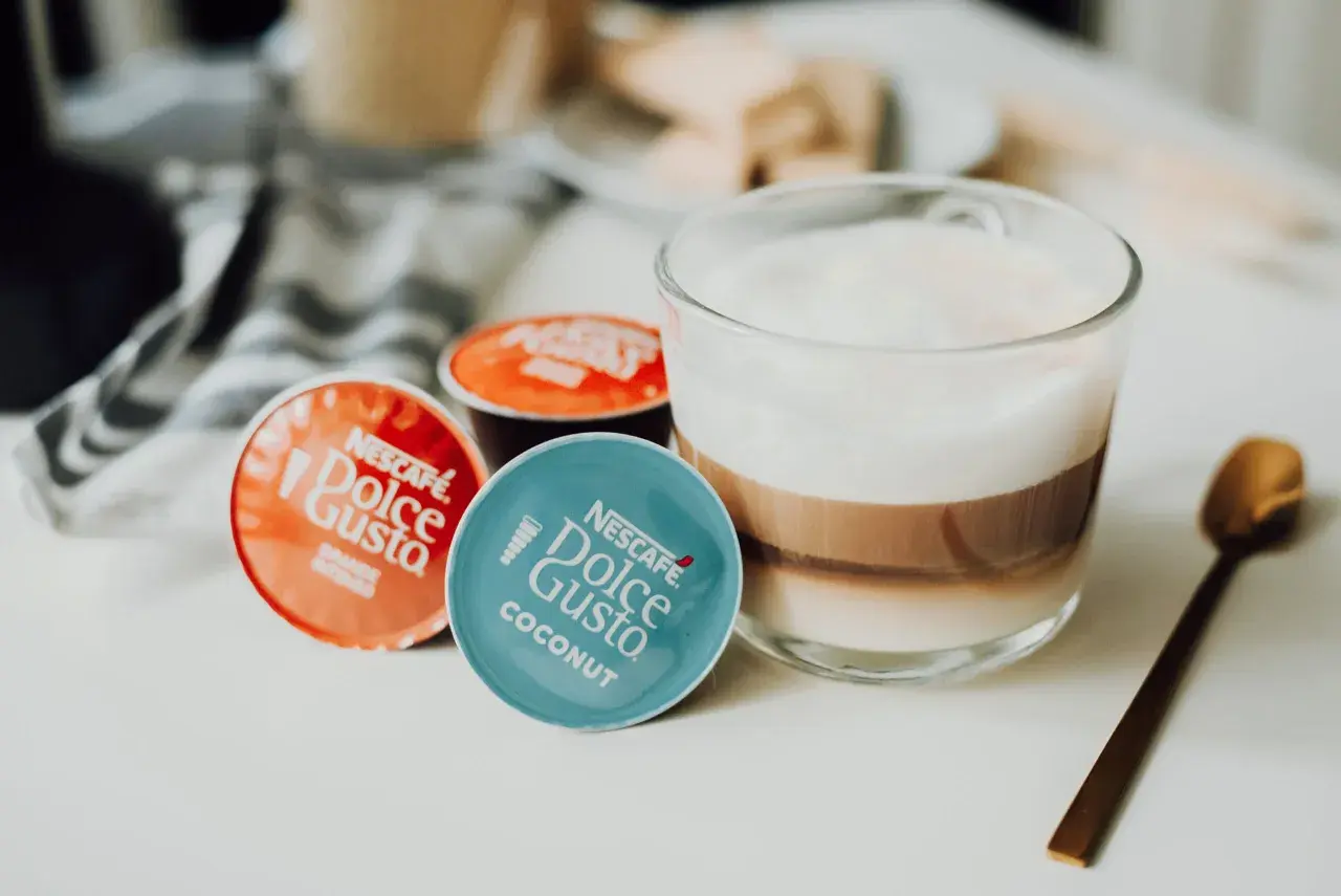 Kapsułki Dolce Gusto obok kawy z mlekiem. Może ekspres Dolce Gusto nie chce wyjąć kapsułki?
