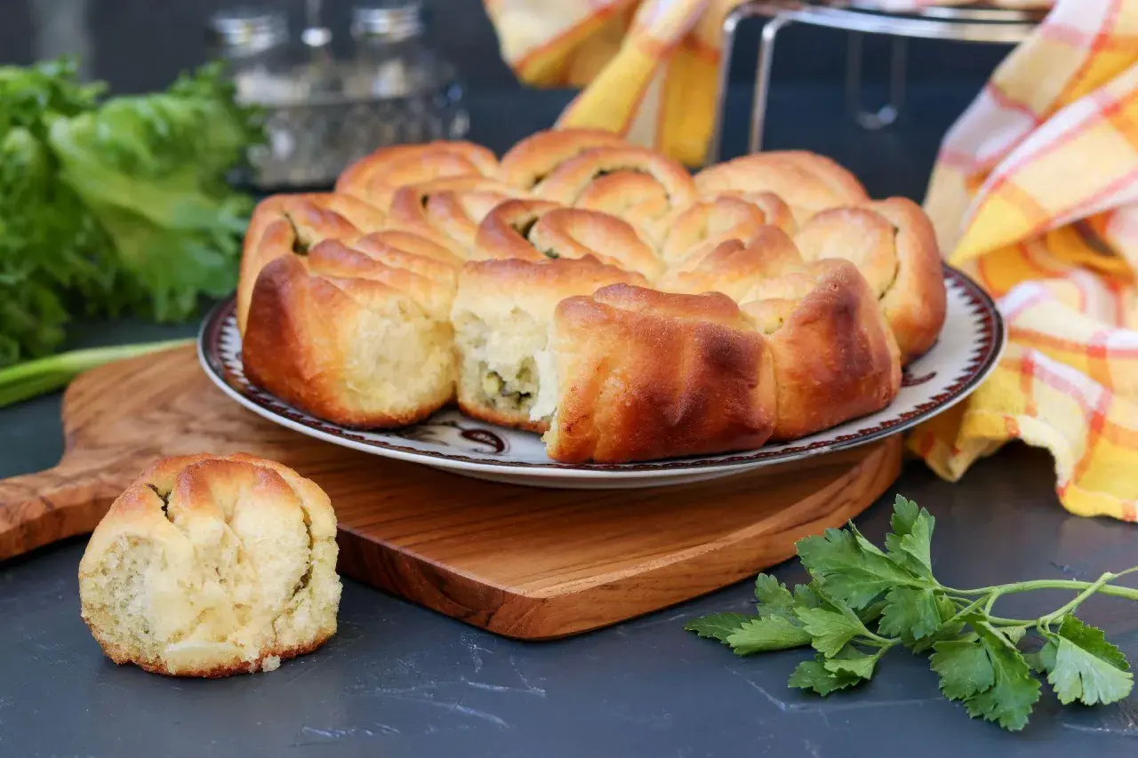 Puszysty chlebek ziołowy z Thermomixa, upieczony na złoto, z zieloną natką pietruszki obok.