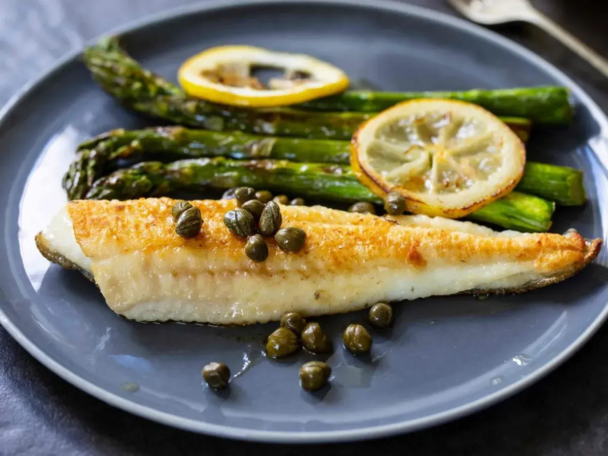 Sogliola in friggitrice ad aria, dorata e succulenta, servita con asparagi croccanti, capperi e fette di limone.