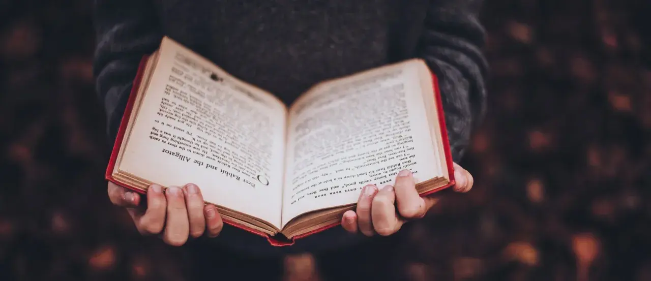 Mani che tengono un libro aperto con testo in inglese, forse uno dei tanti libri premiati che raccontano storie avvincenti.