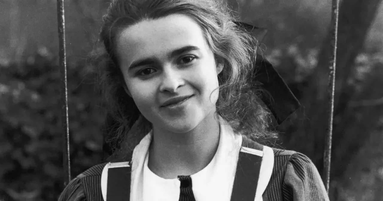 Młoda Helena Bonham Carter z burzą loków i figlarnym uśmiechem, w stroju przypominającym szkolny mundurek.