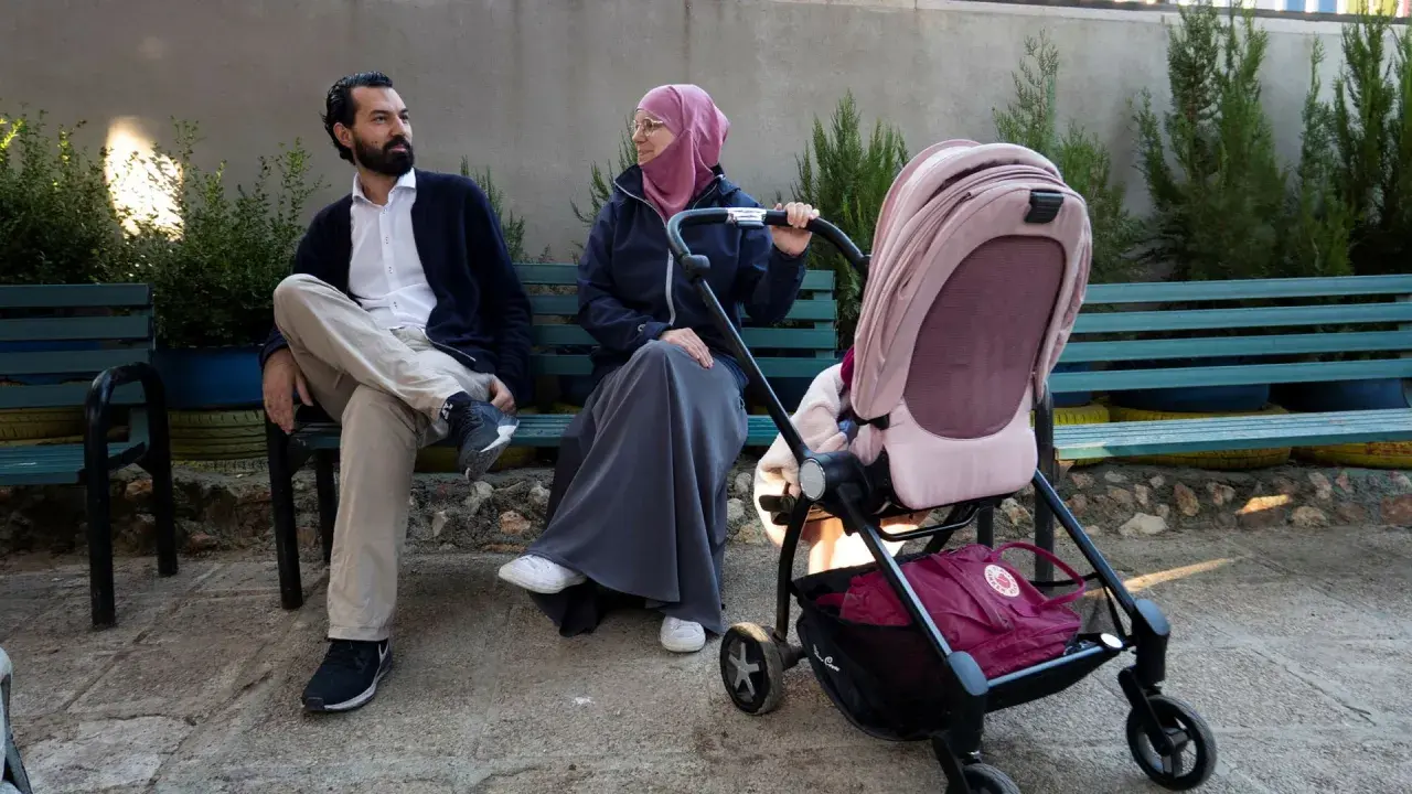 En man och en kvinna, som representerar muslimer i Sverige, sitter på en bänk med en barnvagn.
